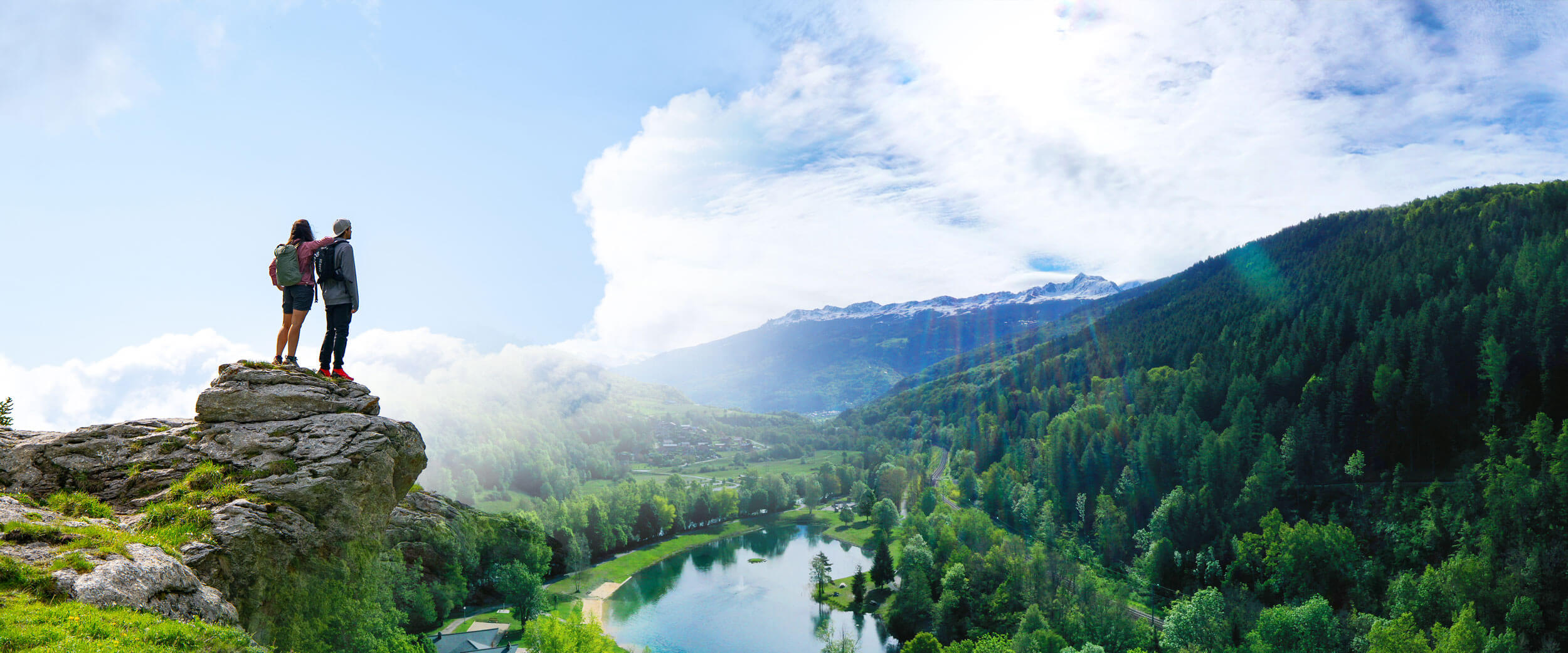 Montage entre deux photos : un panorama du plan d'eau de Macôt La Plagne avec une vue sur les Arcs ; et deux randonneurs au sommet d'un rocher contemplant le paysage.